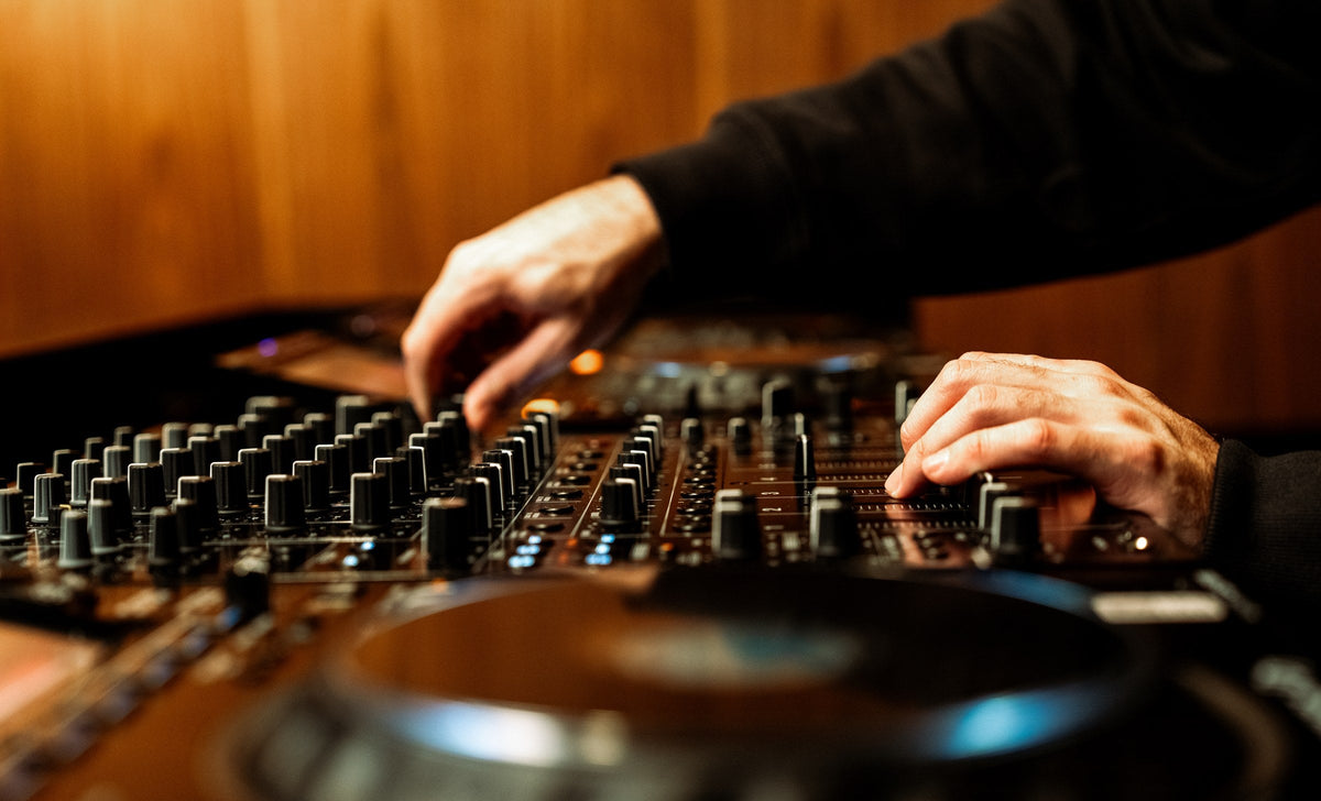 Dos manos mezclando en el mixer del Studio 01 de dbel